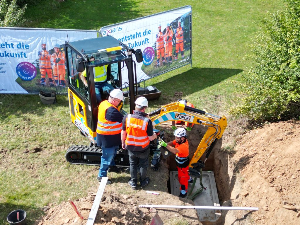 Zukunft des Bauens: Beim Pilotprojekt zwischen Rösrath und Hünfelden kommen erstmals vollständig elektrische Baumaschinen für den Gigabit-Ausbau zum Einsatz – mit messbaren Vorteilen für Umwelt und Anwohnende. Quelle: Axians Deutschland 